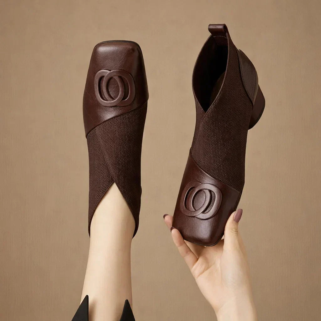 Brown square-toe ankle boots with elastic sides and embossed circular logo detail
