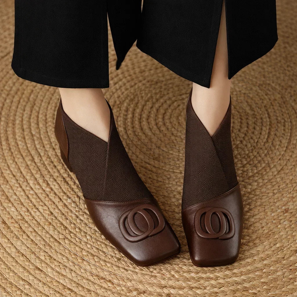 Brown square-toe ankle boots with elastic side panels and embossed circular logo