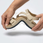 Beige cushioned sandal with hook strap and textured footbed, side view