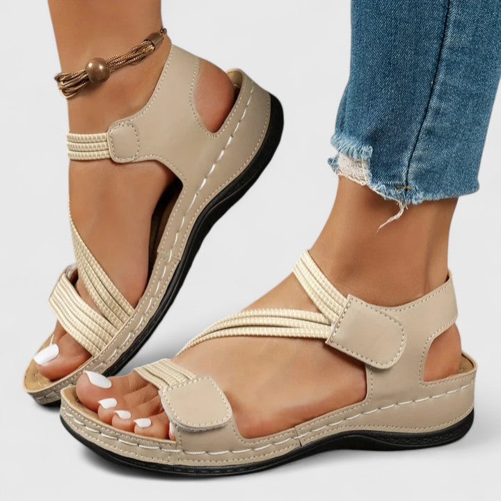 Beige cushioned wedge sandals with ankle strap and open toe, black-trimmed sole