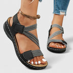Black cushioned wedge sandals with adjustable ankle strap and open toe, braided detail