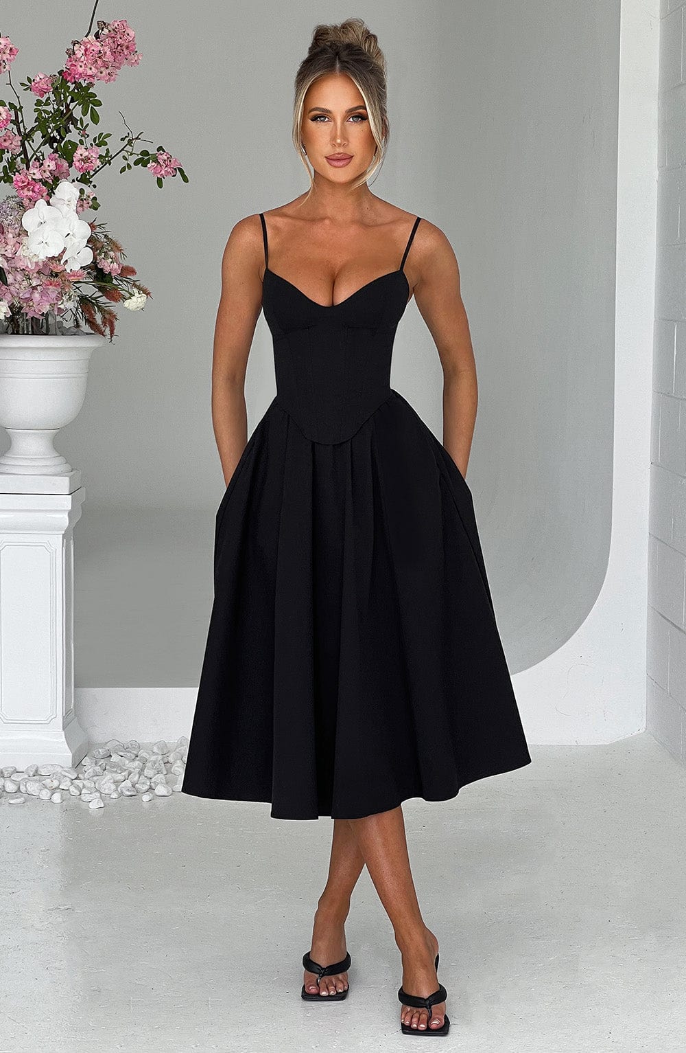 Black corset midi dress with spaghetti straps and fitted bodice, full pleated skirt