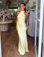 Yellow satin halter neck maxi dress with fitted waist and floor-length straight skirt