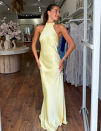 Yellow satin halter neck maxi dress, sleeveless and fitted with side slit at hem