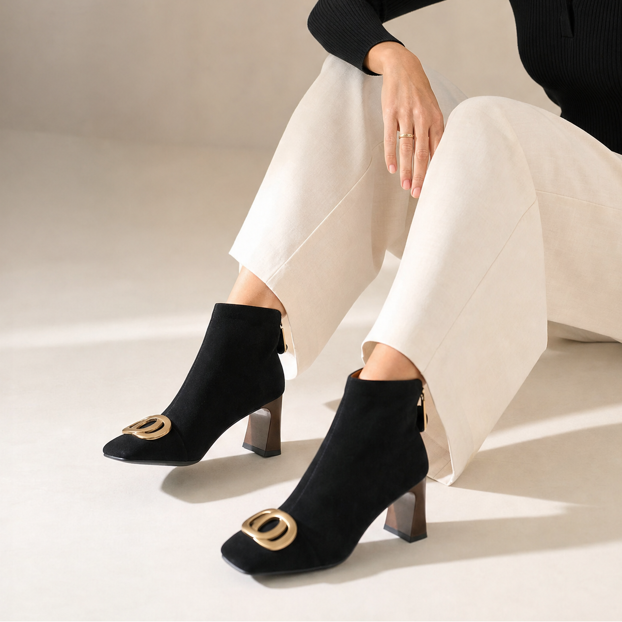 Black velvet ankle boots worn with cream pants; gold O-ring buckle and block heel