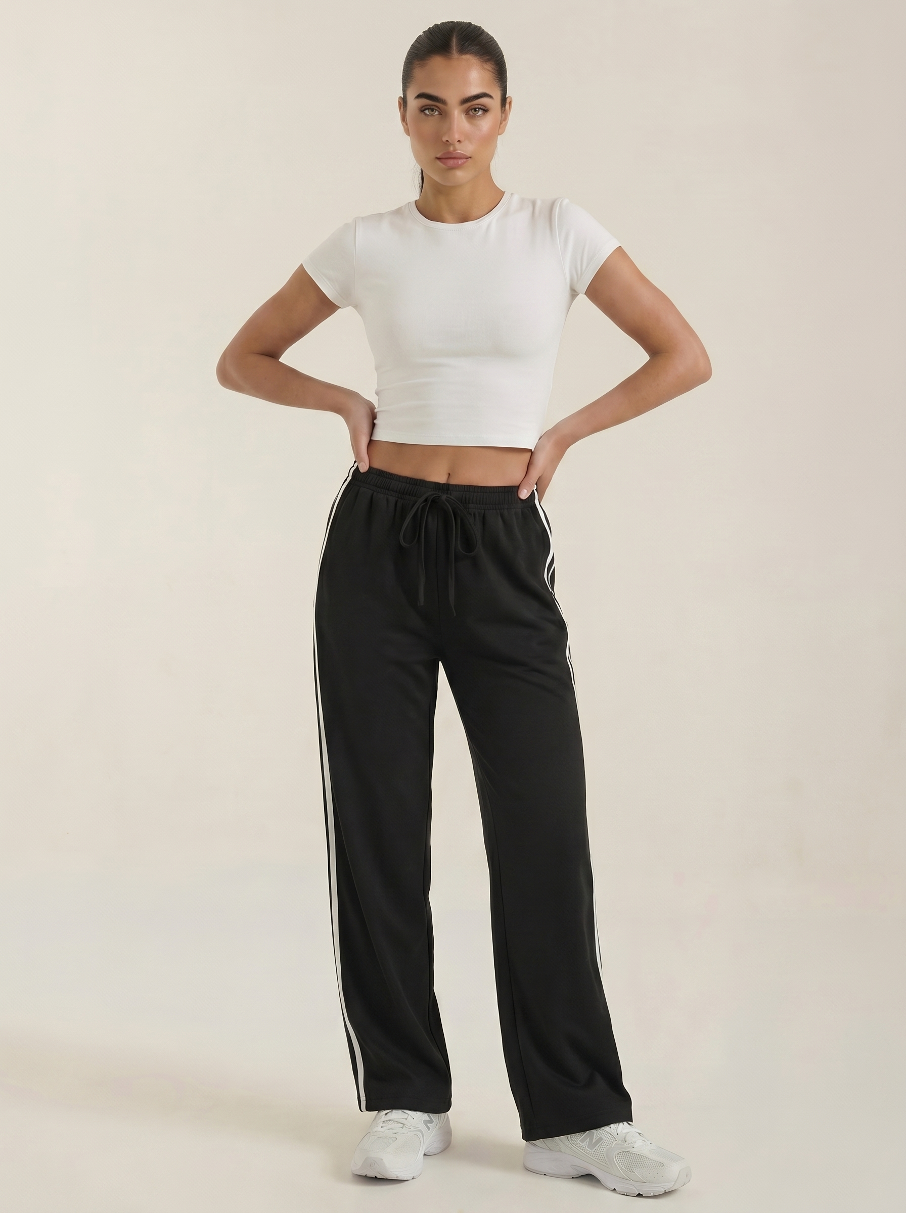Black wide-leg track pants with elastic waist, drawstring, and white side stripe