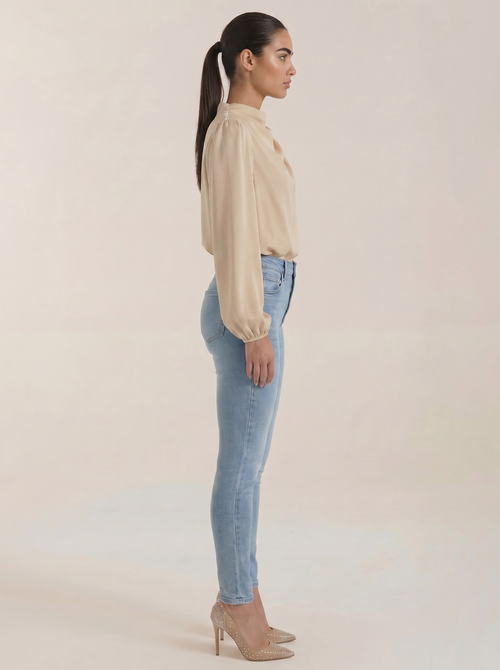 Beige draped long-sleeve blouse viewed from the side, with cowl neckline
