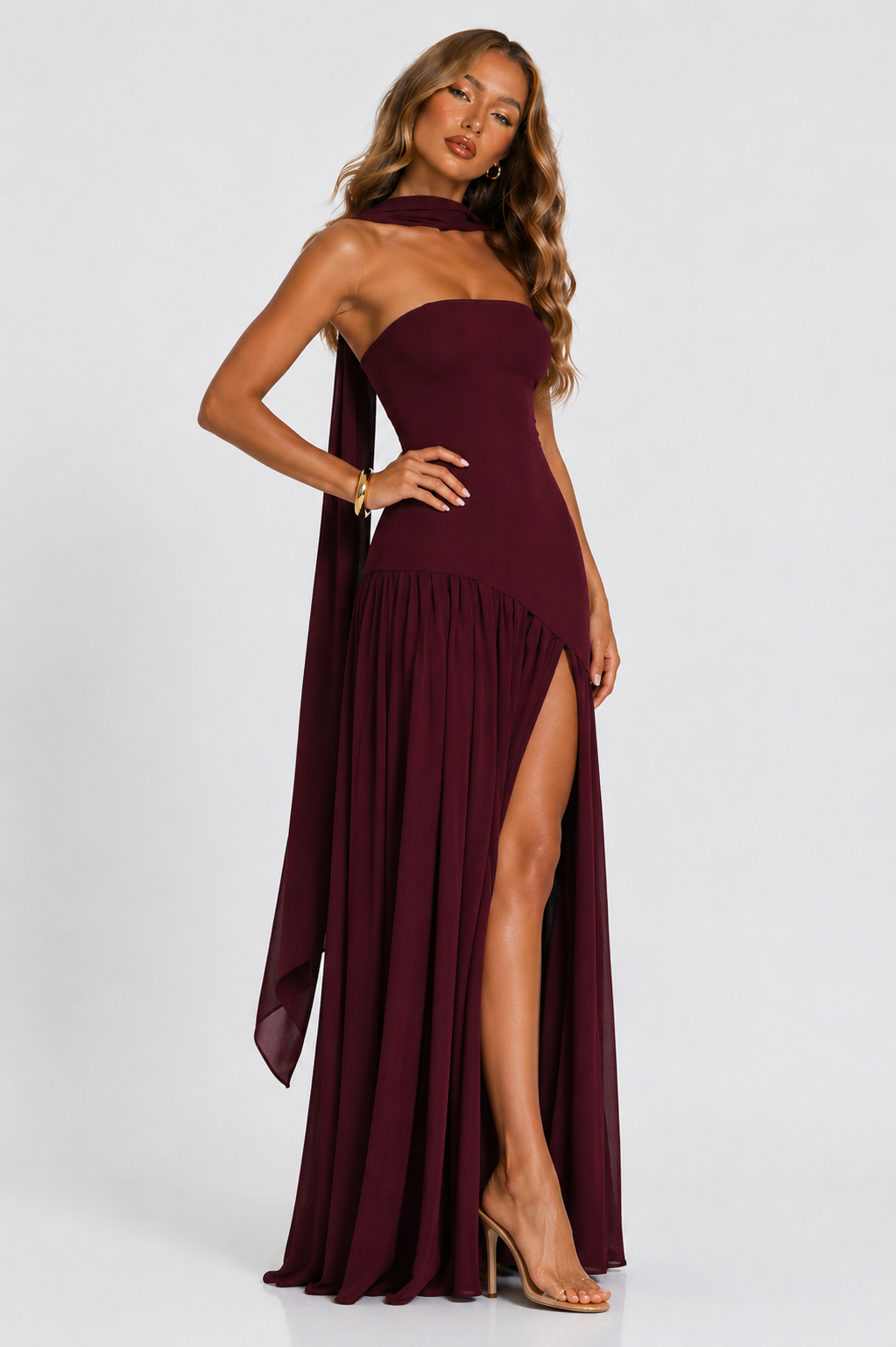 Burgundy strapless maxi dress with pleated skirt and high side slit with draped panel